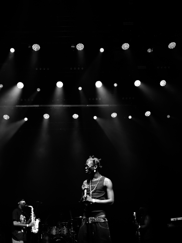Black and white high-contrast shot of Seyi Vibez on stage with rows of spotlights visible overhead. — concert photography London by Lamss Media